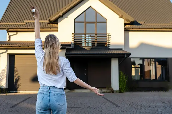 Žena s kľúčmi pred novým rodinným domom – symbol pre domy na kľúč